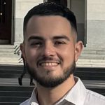 Latino man with beard and cream-colored button down shirt in front of California State Capital