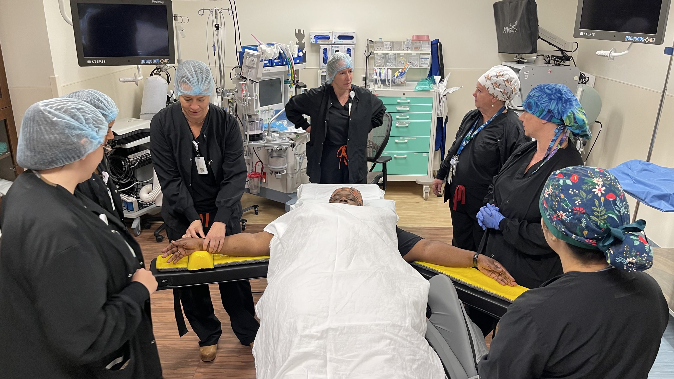 Numerous people in scrubs and masks inside an operating room