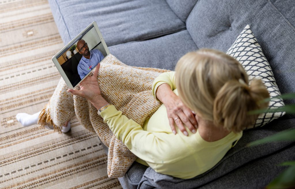 Woman on couch consults with doctor via video visit
