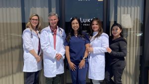 A group of medical professional pose for a photo in front of health clinic