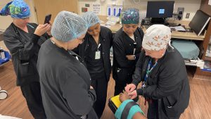 Nurse demonstrates at a training for other nurses how to safely remove a patient’s ring before surgery