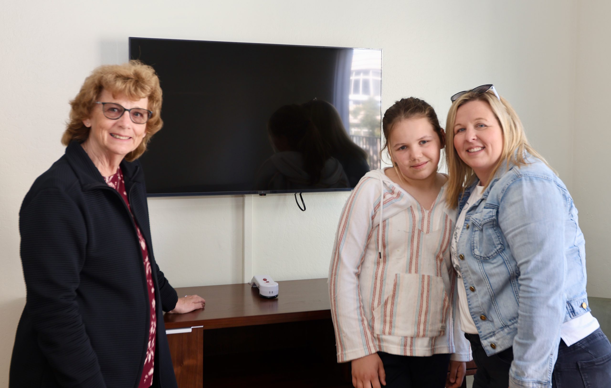 Two women and a child standing in front of an upgraded tv