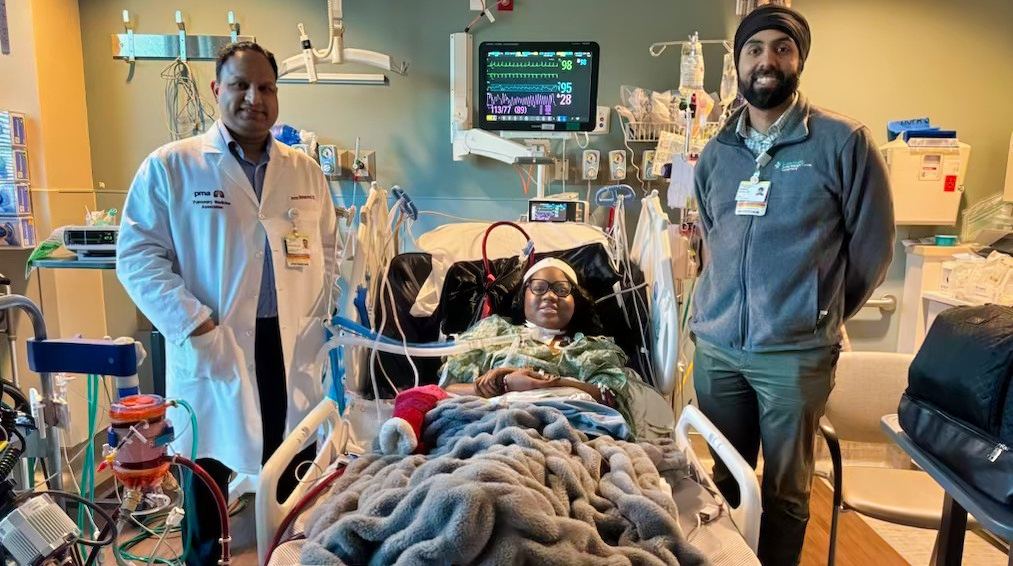 Woman in hospital bed with doctors flanking her.