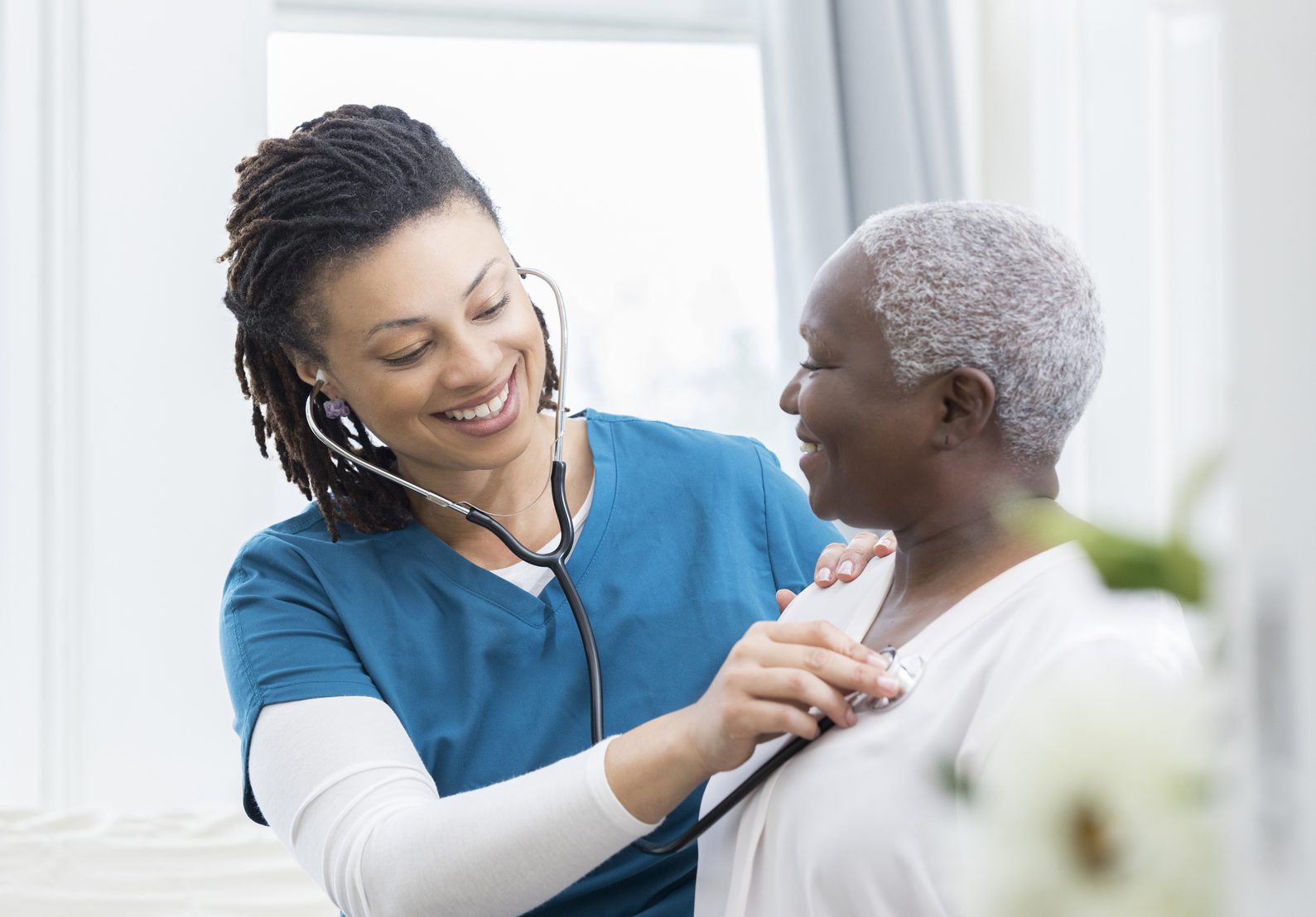 Black female nurse checks Black patient's vital signs