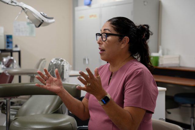 Latina instructor addresses students in a medical teaching lab.