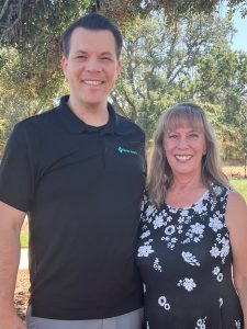 Man and woman pose for a picture outside at a park