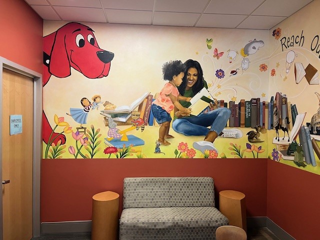 An image of a doctor's office waiting room that is painted with an image of a mother reading to her daughter and Clifford the Big Red Dog