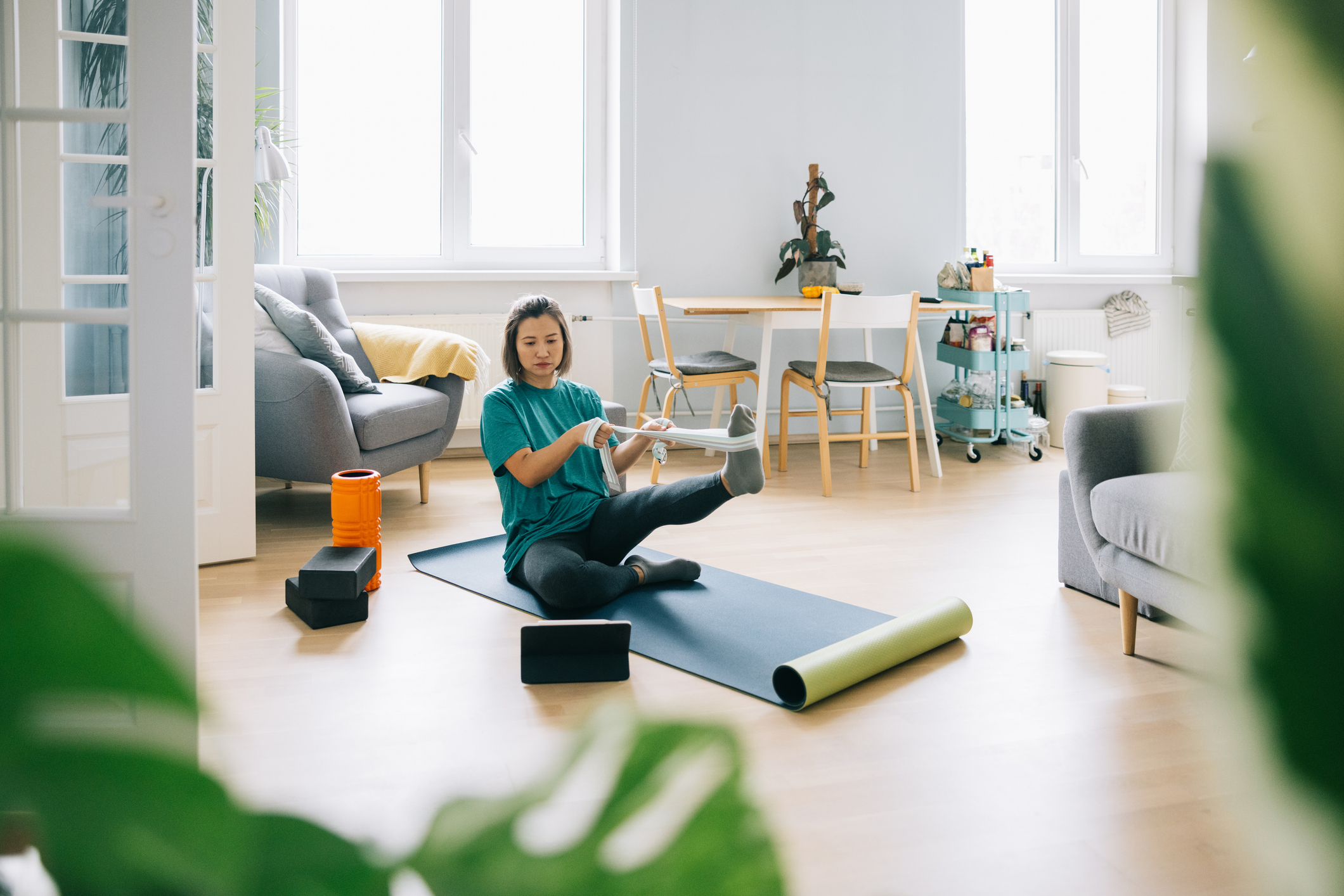 Mid adult Asian woman doing physical therapy at home and using digital technological device