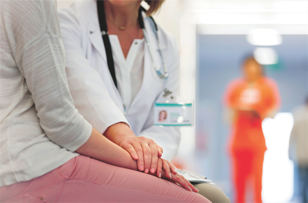 Doctor places hand on patient's hand