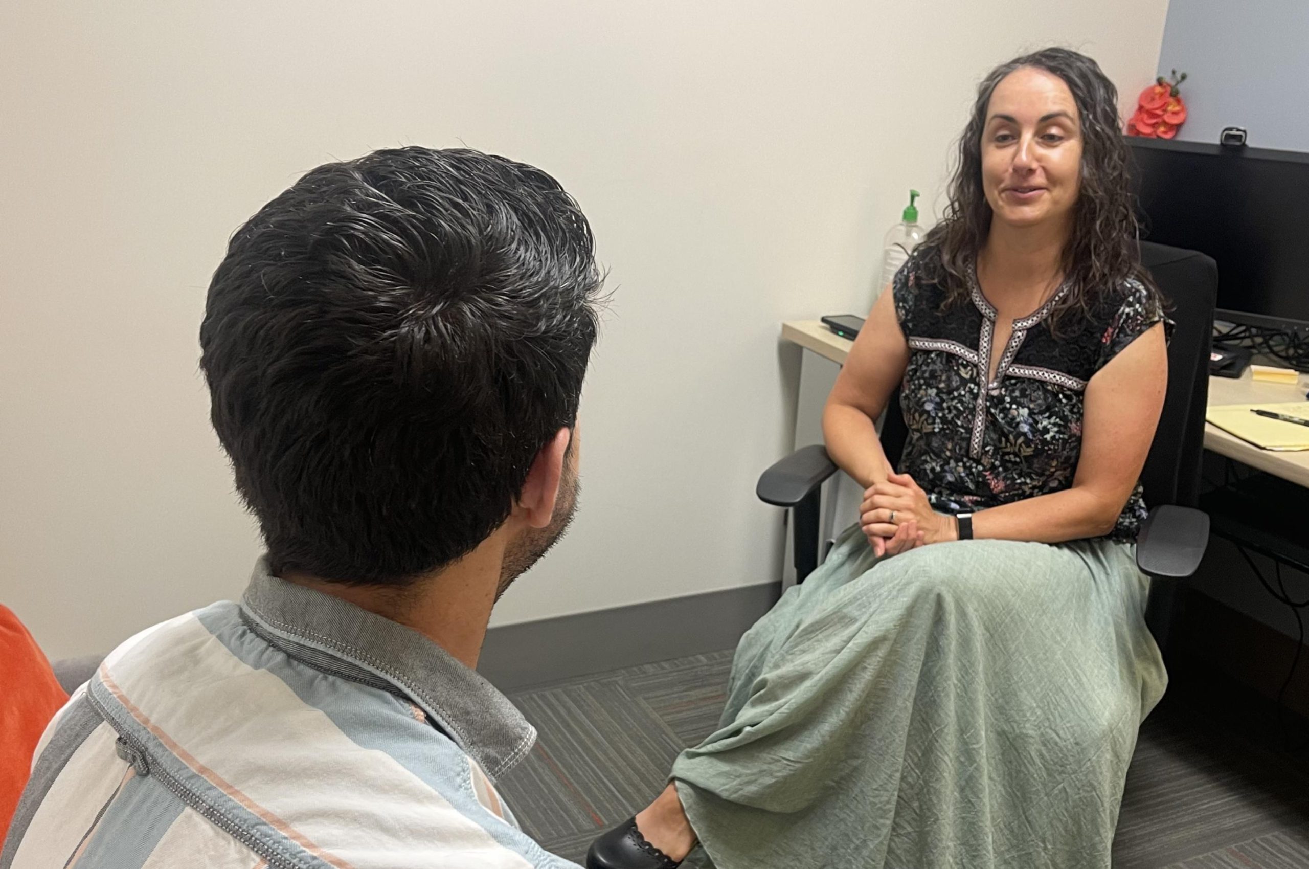 Theresa Rizzo, a woman wearing a green skirt and a dark shirt, is Licensed Psychologist and Axis’s Administrative Director of Integrated Behavioral Health.