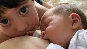 Toddler Lev with his baby sister Eva while she is breastfeeding