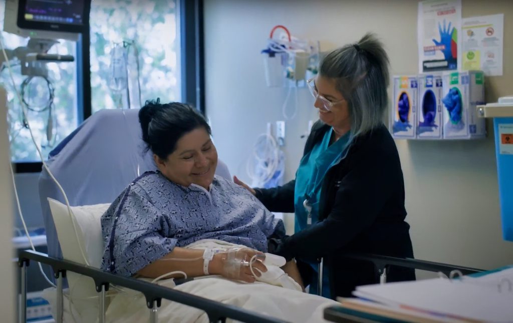 Patient in bed, nurse helping her.