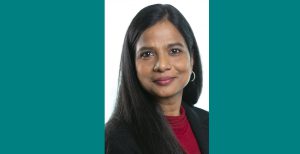 Portrait of Aparna Abburi smiling and wearing a red top and black blazer