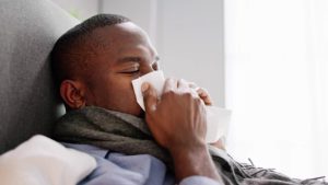 Black man blowing his nose into a tissue