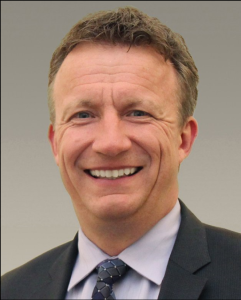 Headshot of white male with strawberry blonde hair and suit and tie