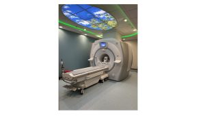 MRI machine with blue sky and greenery imagery above the machine outlined in green light