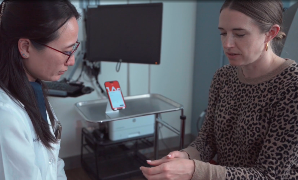 Doctor and patient in room with Abridge software on phone in background