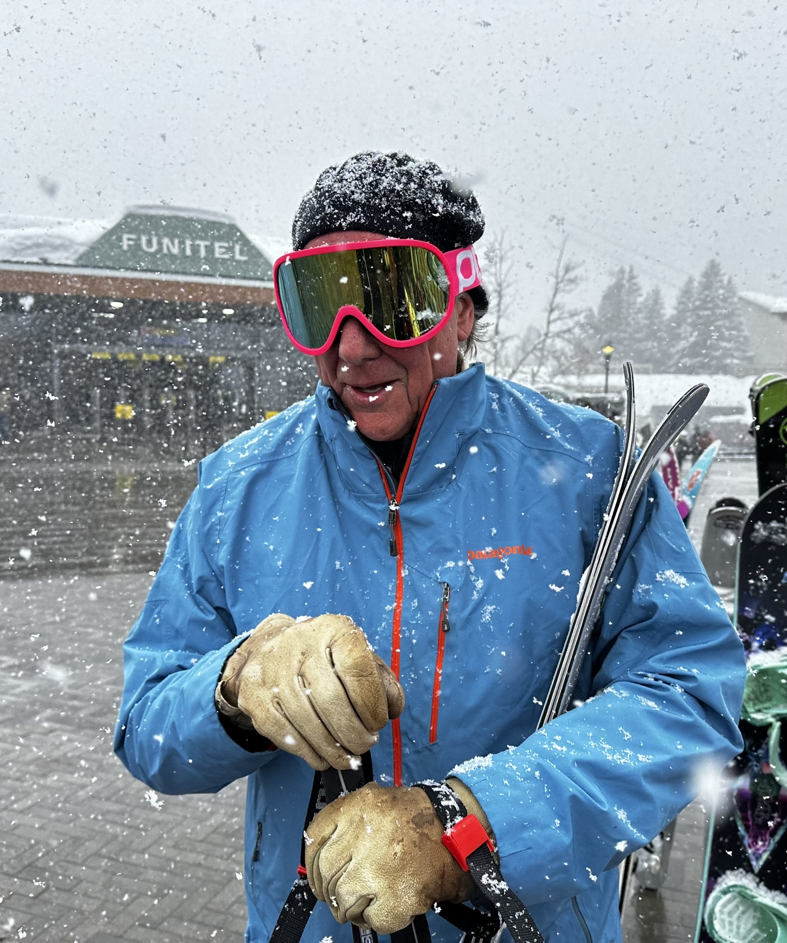 Man in a blue jacket holding skis 