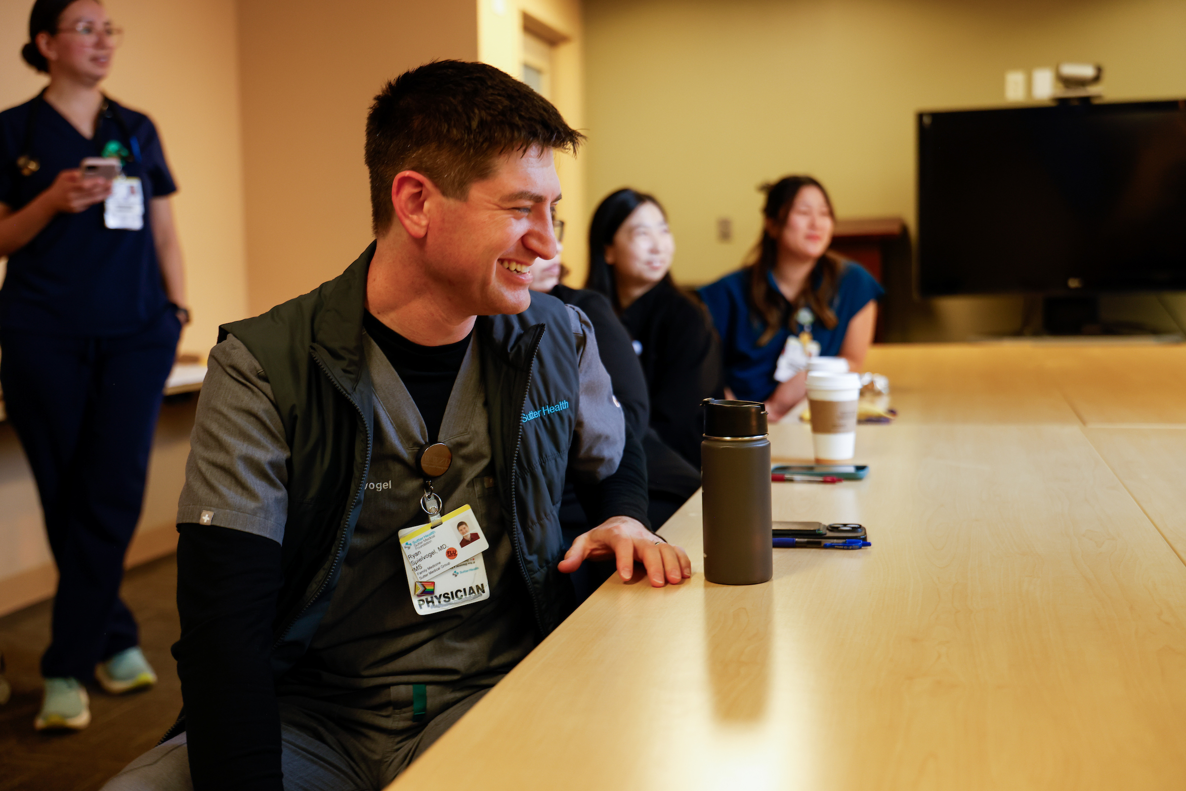 Male program director pictured at table laughing with residents