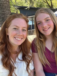 Mother and daughter pose in the outdoors near an outcrop building
