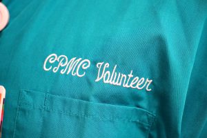 CPMC Volunteer wording is stitched onto teal scrubs