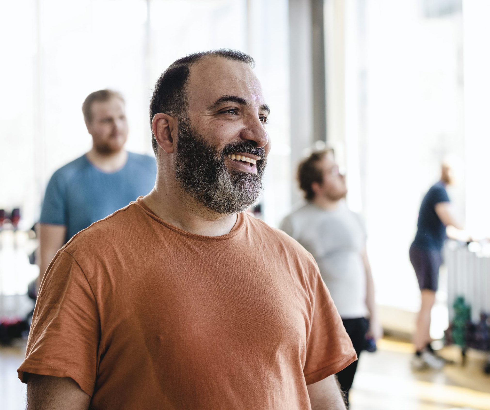 Smiling man looking away with male friends in background at exercise class