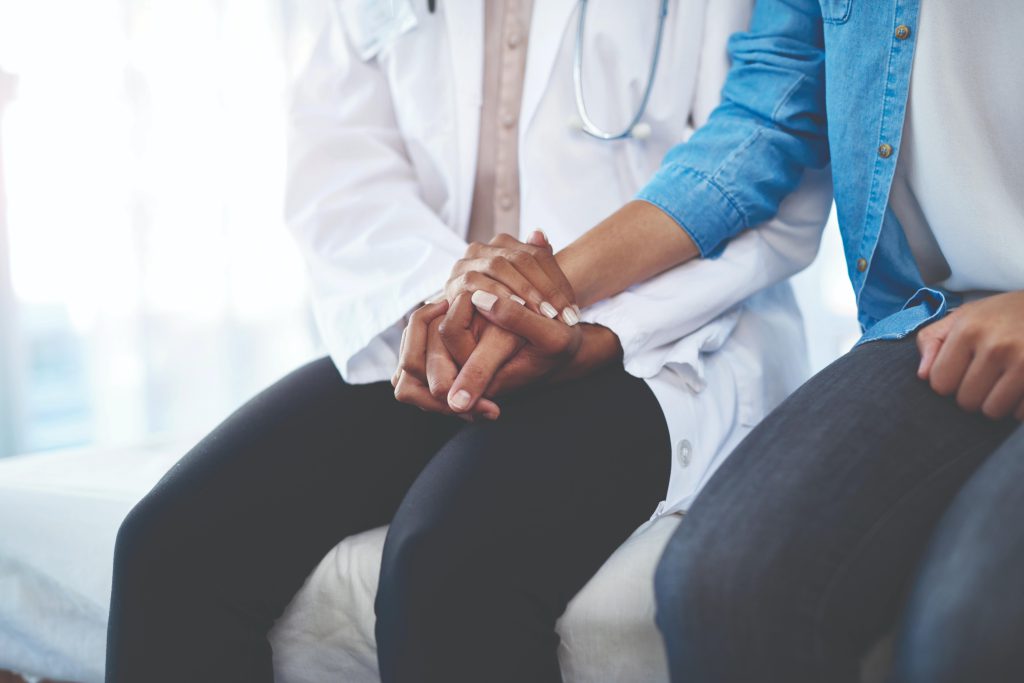 healthcare worker holds patient's hand