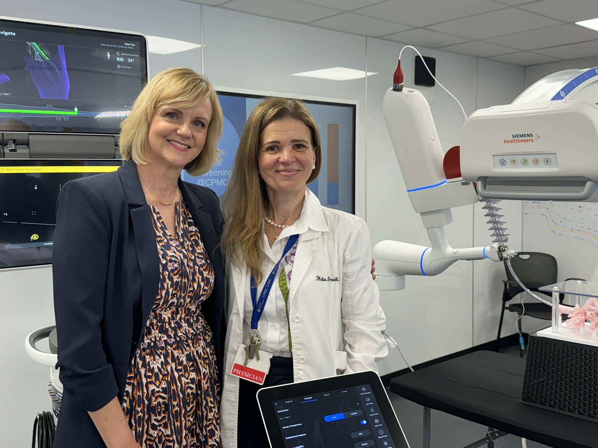 two women stand side by side, one is wearing a doctor's white coat