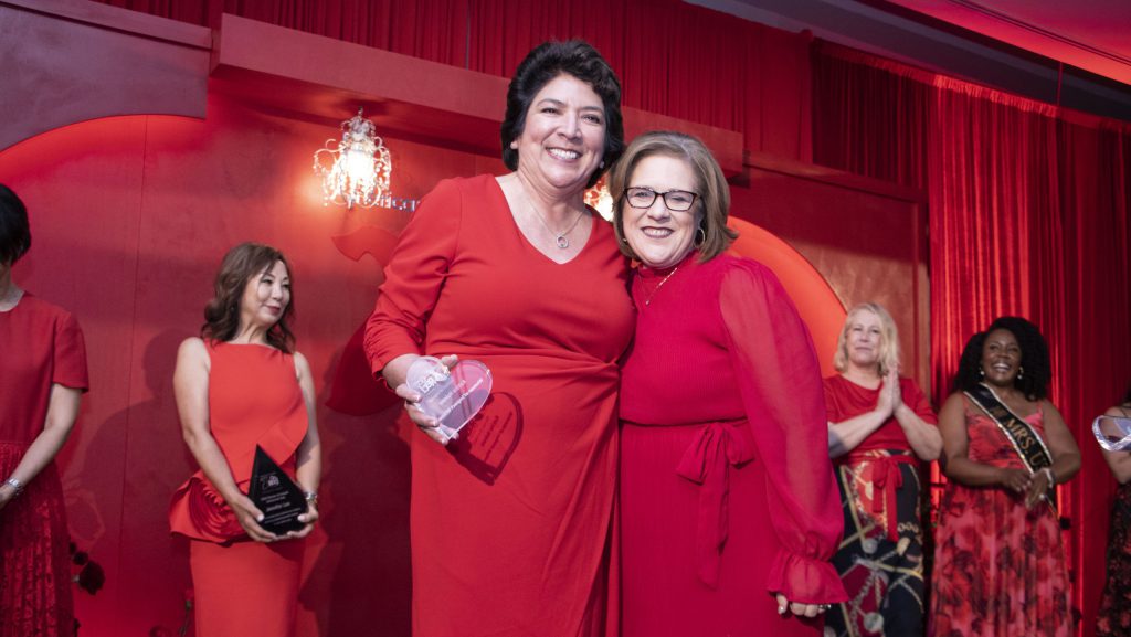 Two women in red dresses strike pose.