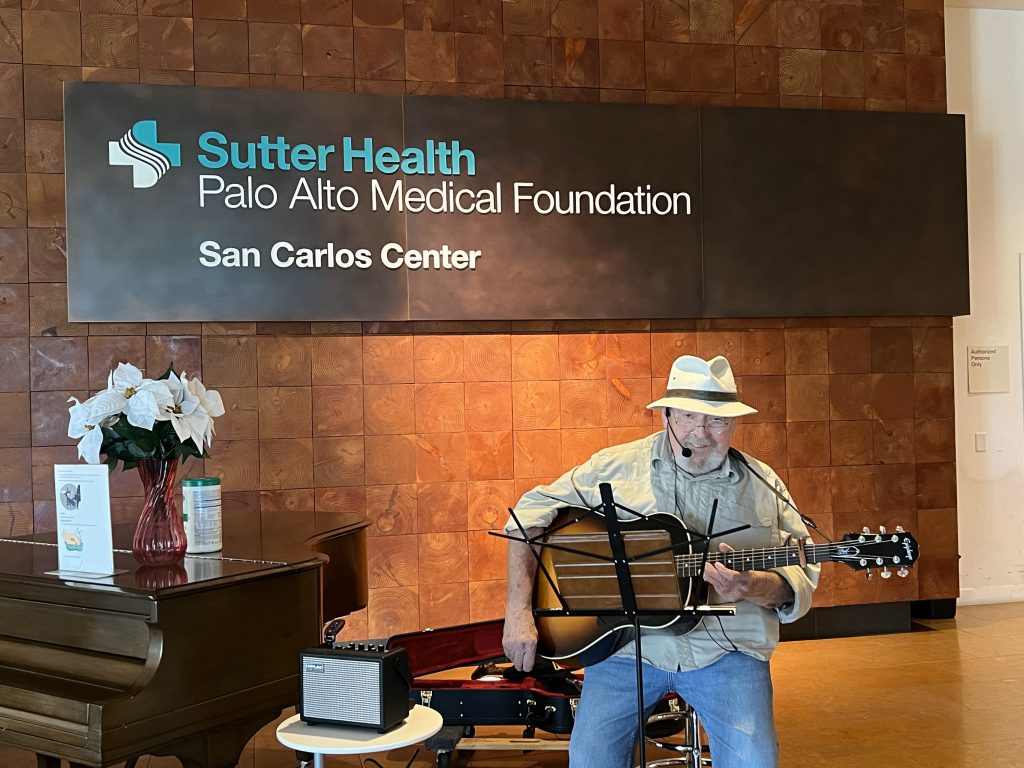 Vance Daddi volunteers to play his guitar in the lobby of Sutter Health Palo Alto Medical Foundation San Carlos Center.