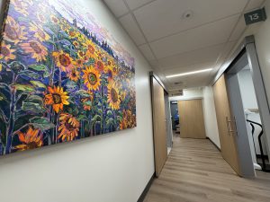 Brightly colored artwork featuring sunflowers in a field adorns a wall inside a patient clinic