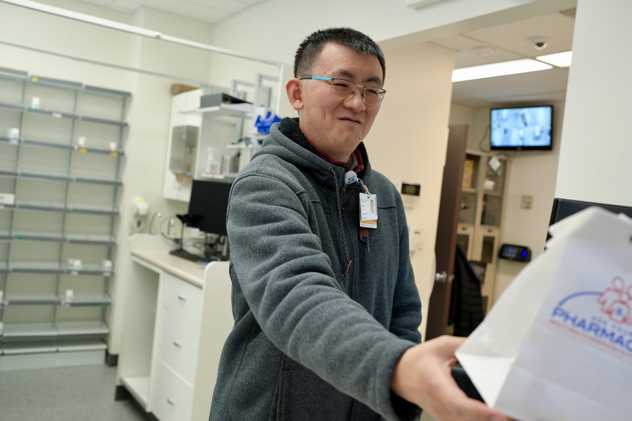 A pharmacy tech hands off a prescription