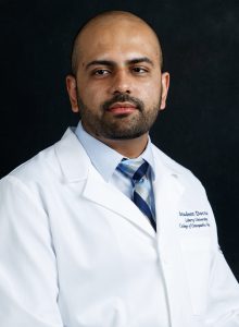 Posed headshot of Southeastern Asian doctor in white lab coat and tie