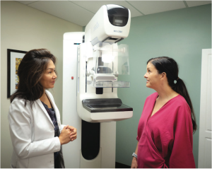 Dr. Winifred Leung speaks to a patient next to a mammography machine