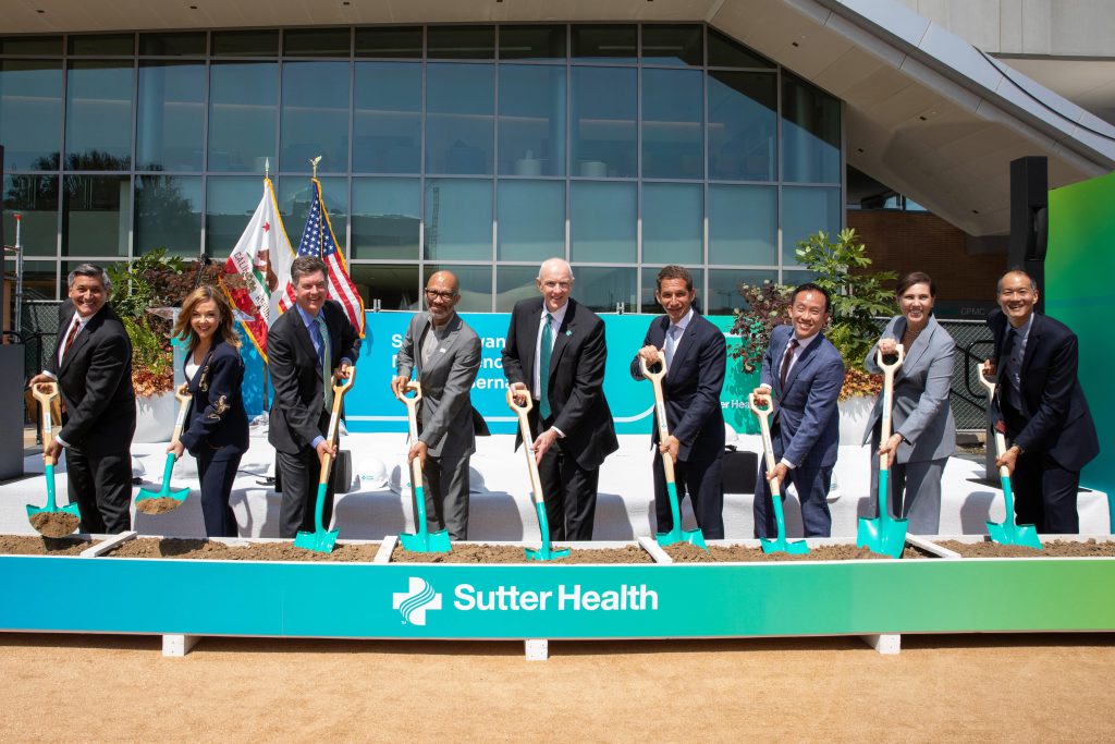 A group gathers with shovels in the ground for a ceremonial groundbreaking