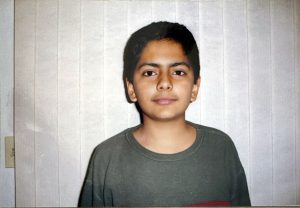 Adolescent Southeastern Asian boy posing inside his home in front of white curtains