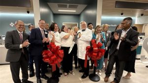 Medical professionals, staff and administrators cut a ceremonial ribbon inside a clinic