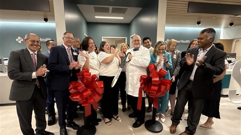 Medical professionals, staff and administrators cut a ceremonial ribbon inside a clinic