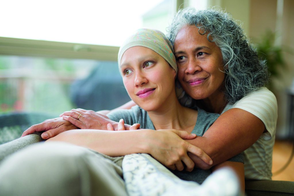 Young woman wearing scarf being hugged by her mother.