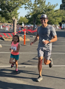 Dr. Adrian Tabares and his daughter share a smile while running.