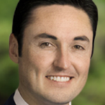 Headshot of a male doctor smiling, green back ground