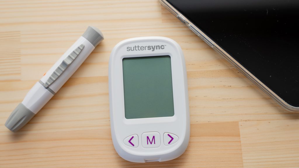 Glucometer on table alongside cell phone