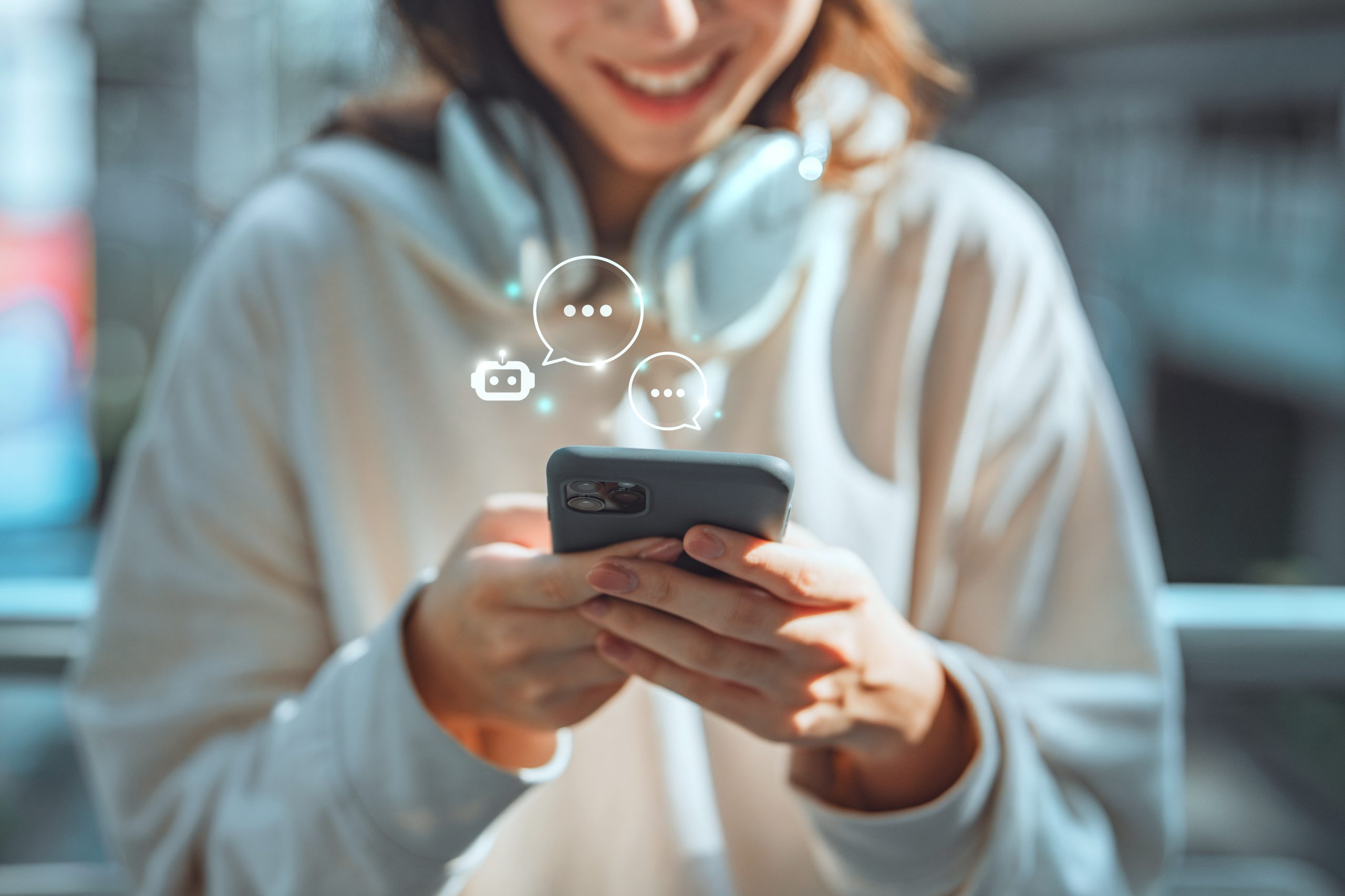 Woman in white hoodie and headphones consults with a chatbot on cell phone