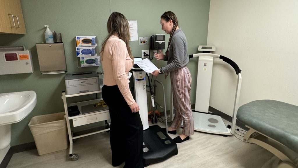 Patient on scale and nurse checking it.