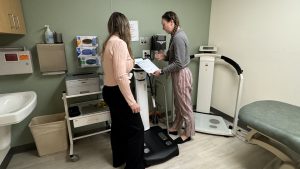Patient on scale and nurse checking it.