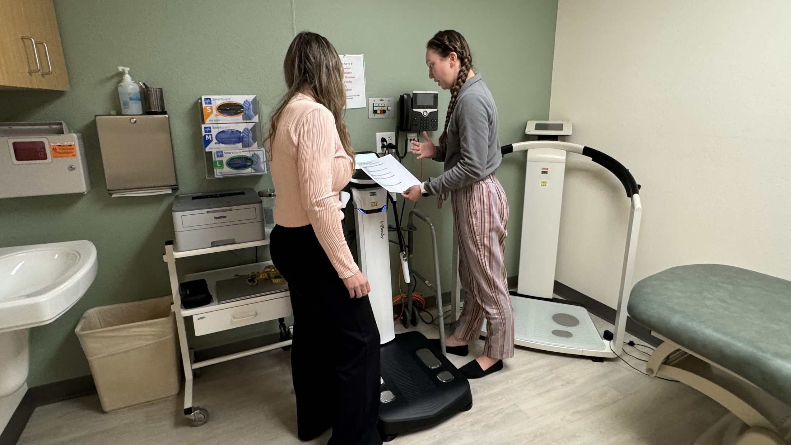 Patient on scale and nurse checking it.