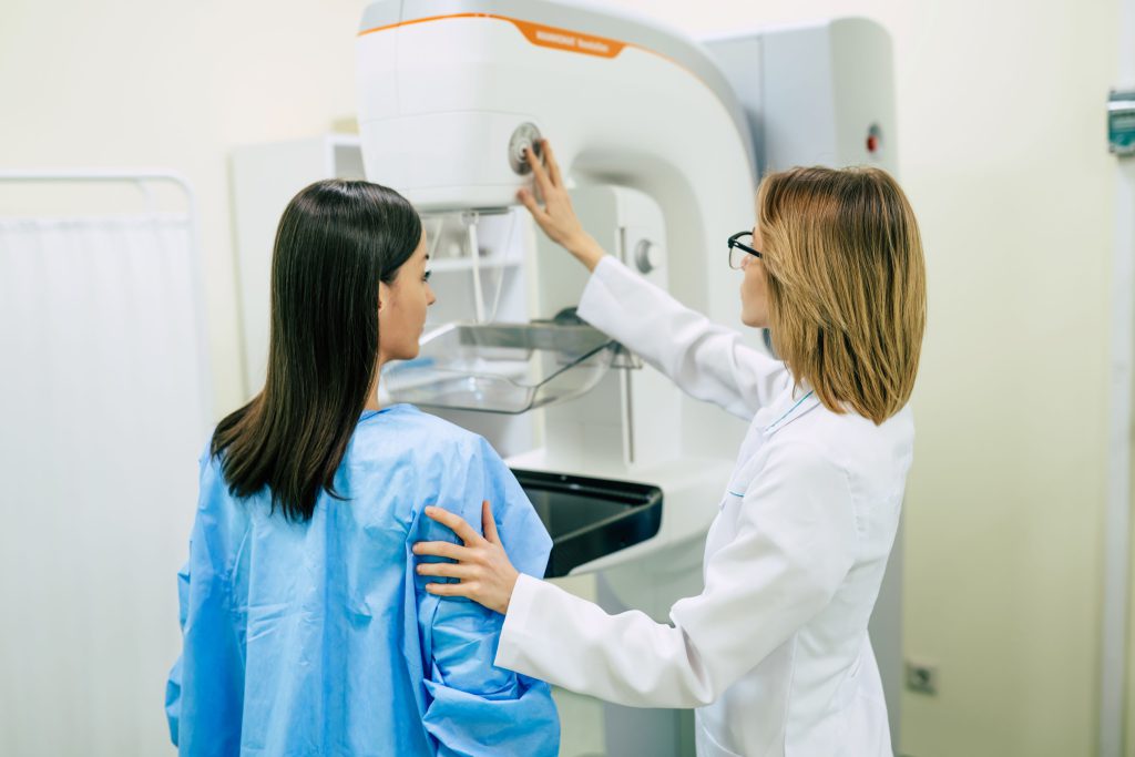 Latina patient undergoes a mammogram screening with the help of a technician