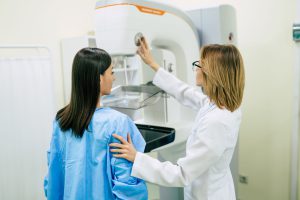 Latina patient undergoes a mammogram screening with the help of a technician
