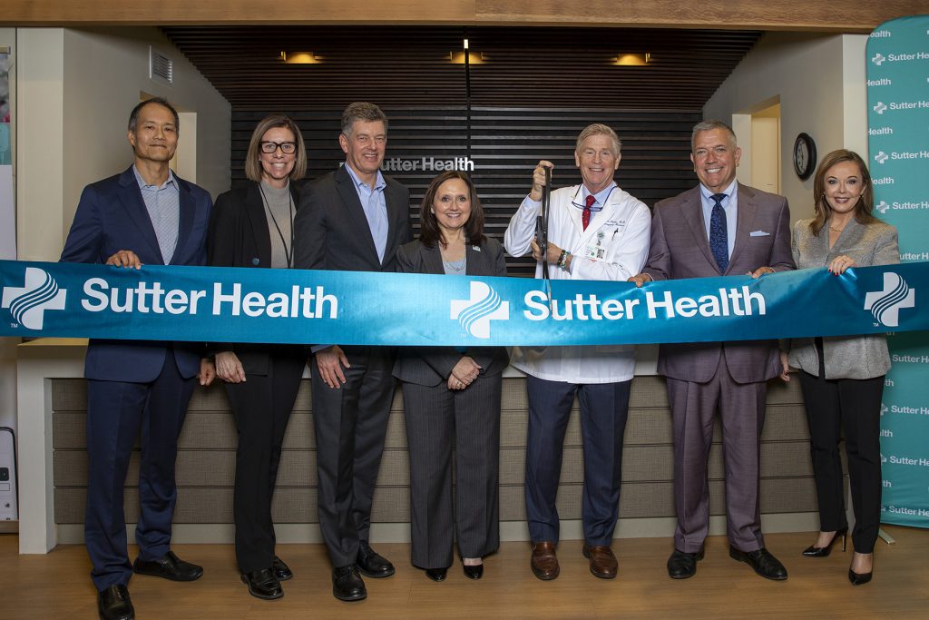 A group of executives cut a ribbon that says Sutter Health