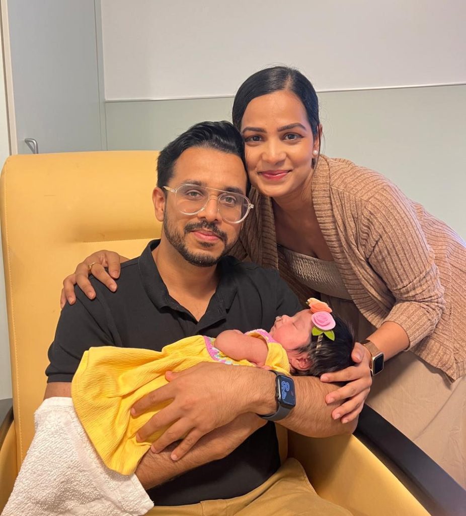 An indian couple holds their newborn baby